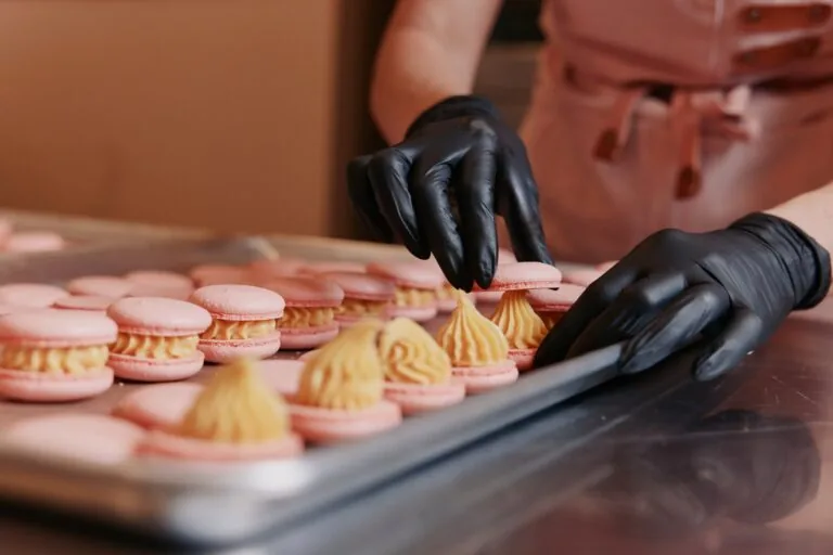 Pink macarons being filled with caramel cream on a baking tray at Honey Birds Bakery