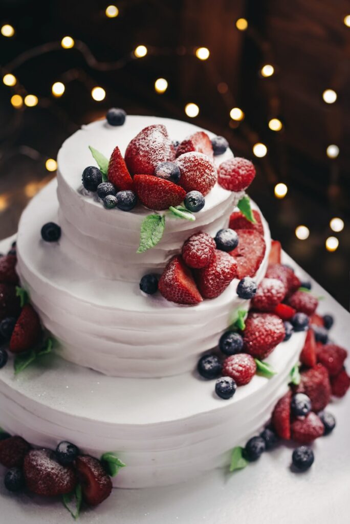 White tiered celebration cake with fresh berries — a Honey Birds custom cake