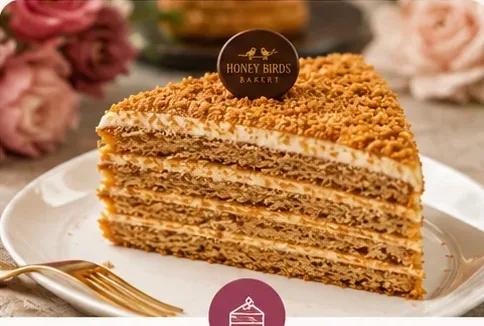 Layered honey cake slice with Honey Birds Bakery medallion